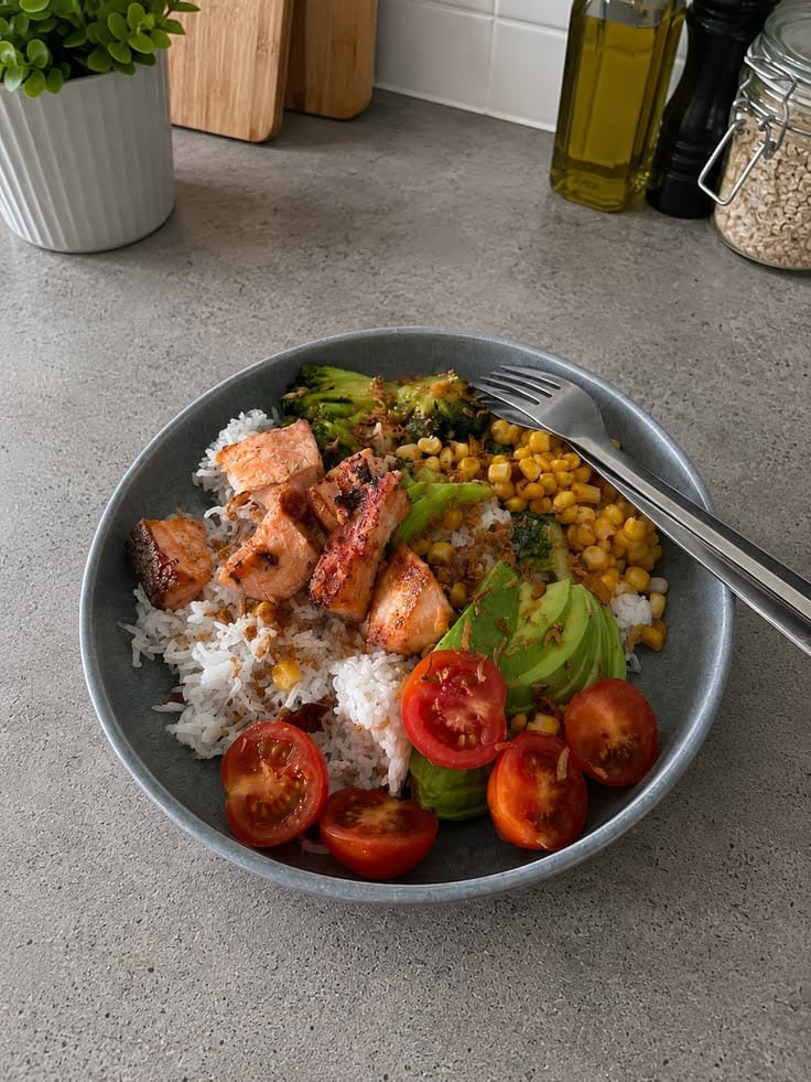 A full plate: salmon, rice, avocado, corn and tomatoes